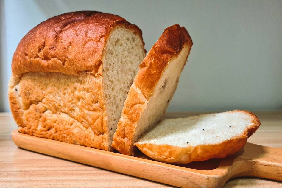 Modern bread machine with fresh artisan loaf on wooden counter