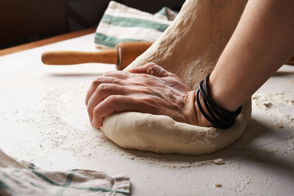 Infographic showing essential vs. optional bread-making tools, including digital scale, dough scraper, banneton, and thermometer