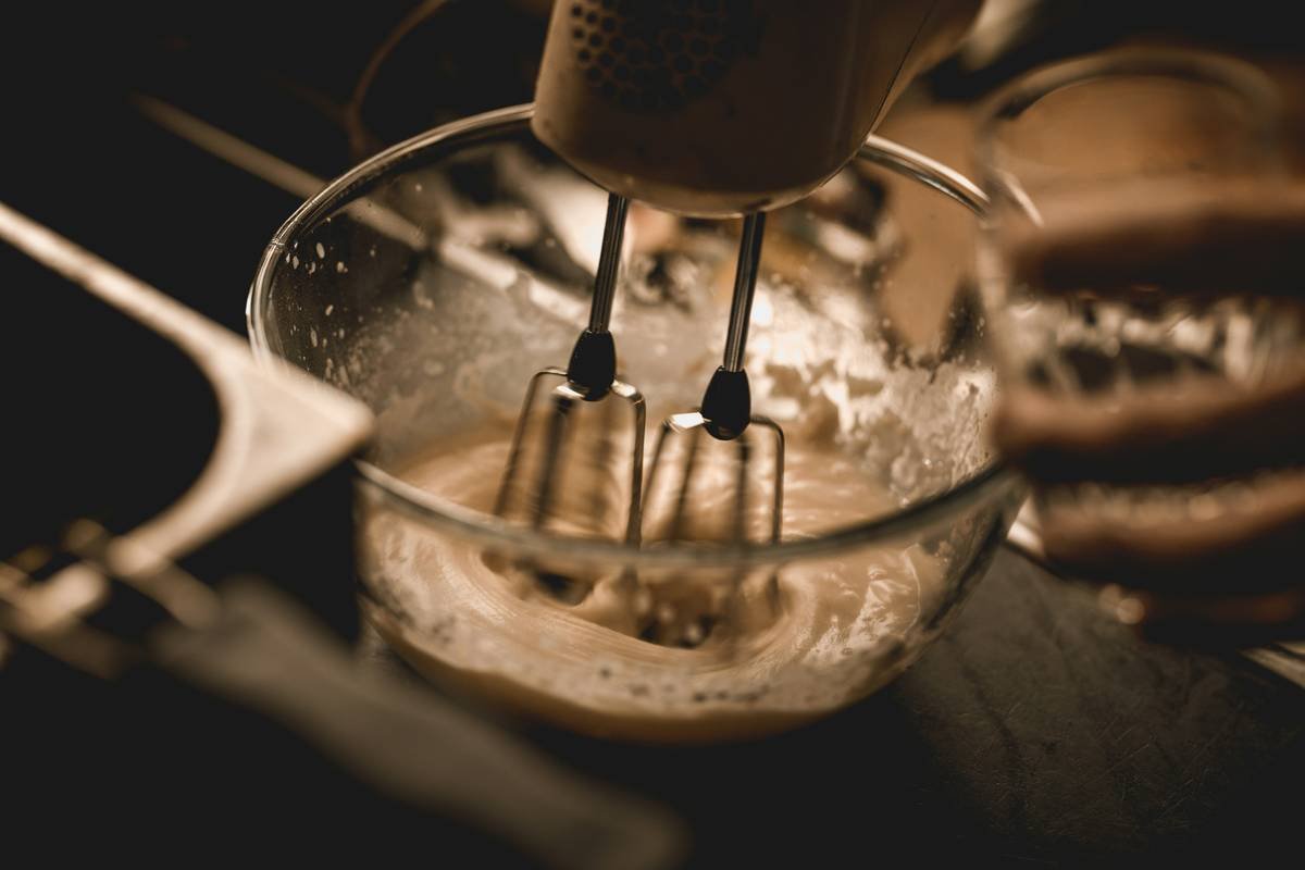 Side-by-side of a bread whisk electric (stainless steel loops) vs a standard balloon whisk struggling in thick dough